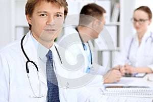 Cheerful smiling male doctor with medical staff at the hospital