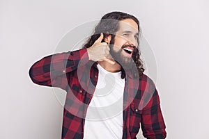 Cheerful smiling man shapes hand like phone, looks gladfully aside, asks for telephone number.