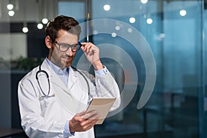 Cheerful and smiling senior doctor in glasses and medical gown reading message