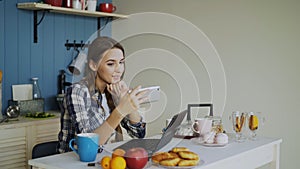 Cheerful smiling woamn talking online video chat using smartphone in the kitchen at home