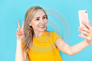 Cheerful smiling woman holding smartphone and showing v sign gesture