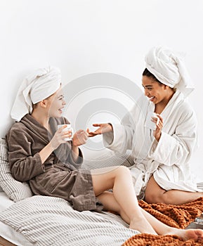 Cheerful spa girlfriends chatting while drinking coffee