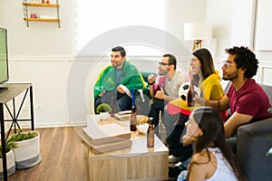 Cheerful sports fans watching their soccer team winning on tv