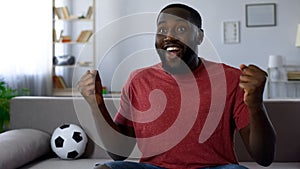 Cheerful sports supporter victoriously screaming watching match on tv, cheering