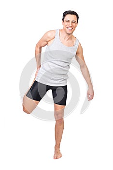 Cheerful sportsman stretching quadriceps muscle