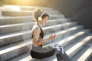 Cheerful sporty girl resting on stairs, training outdoors