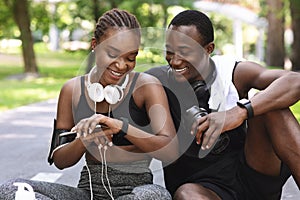 Cheerful Sporty Black Man And Woman Checking Fitness Tracker After Training Outdoors