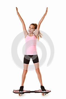 Cheerful sporty teen girl standing on waveboard with hands up,isolated