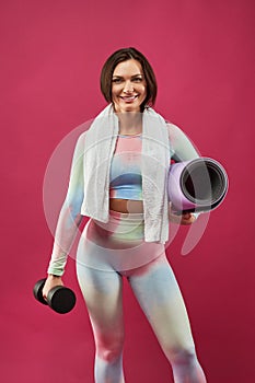 Cheerful sporty woman posing with yoga mat
