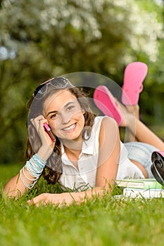 Cheerful student girl lying grass calling phone