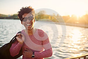 Cheerful student wearing sunglasses smiling near a lake