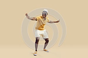 Cheerful stylish african american man having fun dancing on light beige background. photo