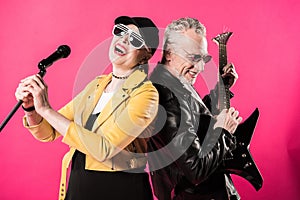 Cheerful stylish senior couple of rock and roll musicians performing