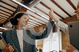 Cheerful successful businesswomen giving five celebrating project victory in modern office