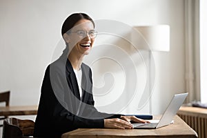 Cheerful successful manager in formal jacket working at laptop