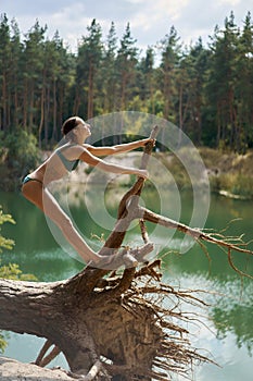 Cheerful Summer Girl Posing on Fallen Tree by Lake in Forest