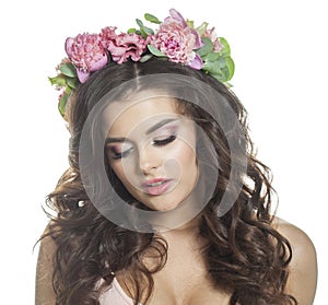 Cheerful summer woman with long dark wavy hair, clean shiny skin and pink flower crown, studio portrait.