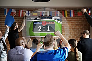 Cheerful supporters watching football at the pub