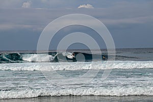 Cheerful Surfer Riding Big Foaming Ocean Wave in Sunny Nature. Man surfing on a cool surfboard in the summer sun near the idyllic