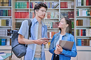 Cheerful talking college students male and female inside library