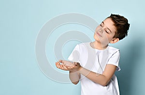 Cheerful teen boy with dark hair and charming smile reaching hands out asking or begging for something.