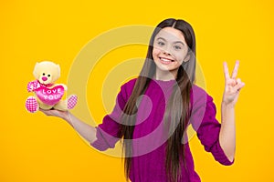 Cheerful teen child hold toy. Happy childhood. Kid playing toy. Teen with toy teddy bear with love heart for valentines