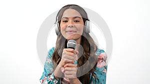 cheerful teen girl in headphones with microphone talk to camera interviewing or singing, technology