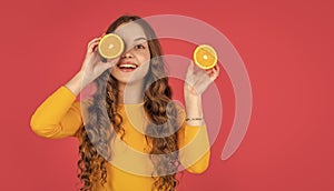 cheerful teen girl hold orange fruit on pink background