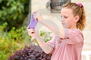 Cheerful teen girl holding a purple slime and looking through.