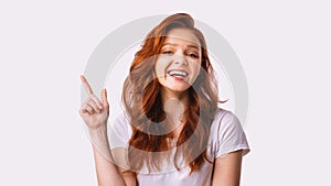 Cheerful Teen Girl Pointing Finger Up Posing Over White Background