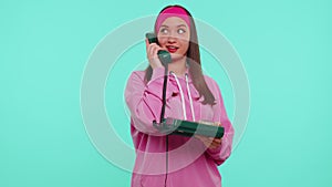 Cheerful teen girl secretary talking on wired vintage telephone of 80s, says hey you call me back