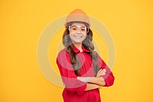 cheerful teen girl wear eyeglasses and helmet. kid future engineer on yellow background.