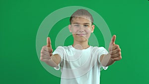 Cheerful teenage boy gesturing thumbs up over green screen chroma key background. Like, agreement, approval concept