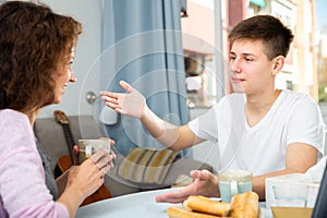 Cheerful teenage boy telling story to mother