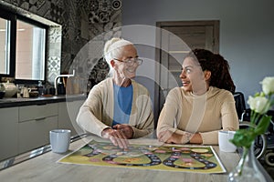 Cheerful teenage girl looking at smiling grandmother while playing leisure game