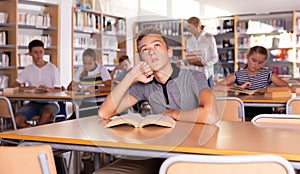 Cheerful teenage schoolers reading and writing