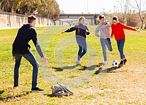 Cheerful teenagers are jogning with ball in park