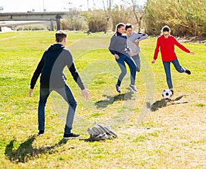 Cheerful teenagers are jogning with ball in park