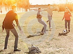 Cheerful teenagers are jogning with ball in park