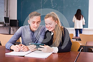 Cheerful teenagers with phone in schoolroom