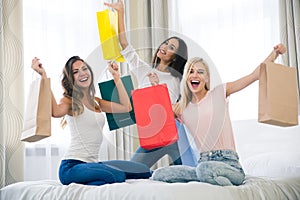 Cheerful three girlfriends with many shopping bags