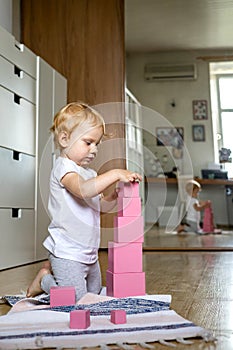 Cheerful toddler arrangement pink cubes assembling tower educational Maria Montessori materials