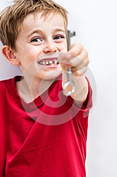 Cheerful toothless boy holding a key forward for fun creativity