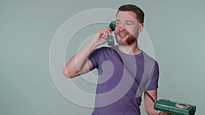 Cheerful tourist man secretary talking on wired vintage telephone of 80s, says hey you call me back