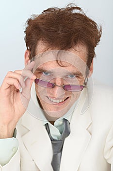 Cheerful tousled guy looks over eyeglasses