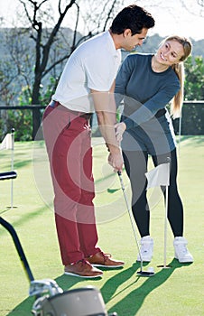 Cheerful trainer showing player how to hit ball