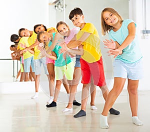 Cheerful tweens standing in row one by one learning funny dance
