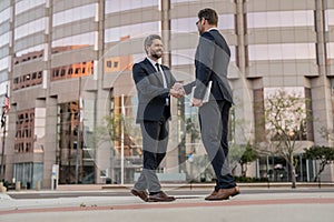 cheerful two business men handshaking. two business men handshaking outdoor.