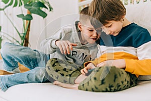 Cheerful two Childs boys playing online game, watching video on cellphone. Smiling kids using funny mobile apps