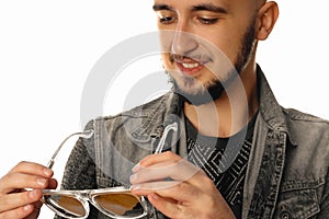 Cheerful unshaved man with sunglasses in hands and smiling